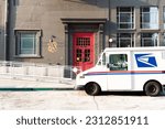 Industrial building with a red door and a US postal service truck parked out front