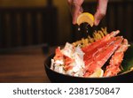 Small photo of Steamed King crab in Japanese style in black bowl. Hand squeeze lemon with lemon juice drop.