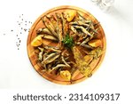 Small photo of Close-up of a delicious dish of Black Sea fried fish - capelin, sprat, swell, gobies on a beautiful wooden plate. Odessa snacks for beer.