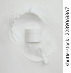 Small photo of Cosmetic container white lotion droplet fly splashing. Milk lotion pour float to cosmetic bottle. Moisturizer lotion explosion spill. White background isolated high speed shutter freeze top view