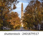 Bennington Battle Monument looking north on a clear Autumn day with Fall foliage draping over the street.
