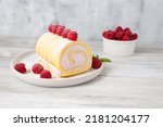 Small photo of Tasty roll cake, sponge roll, Swiss roll stuffed with cream cheese ,decorated with fresh raspberries.