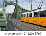 Yellow tram on a green suspension bridge, a tram rides on a metal bridge, Budapest Liberty Bridge, a yellow tram, a bridge over the Danube
