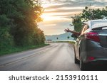 Happy woman waving hand outside open window car with meadow and mountain background. Female lifestyle relaxing as traveler on road trip in holiday vacation. Transportation and travel.