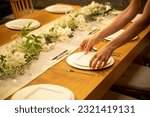 Wedding dinner table preparation. Modern designed plates. Spacious looking wedding table. dining table arrangement. Photos taken from high angles. Photographs of women's hands.