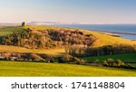 Small photo of Evening sun illuminates the hilltop St Catherine's Chapel at Abbotsbury in Dorset, with Chesil Beach and the Isle of Portland on the English Channel's Jurassic Coast behind.