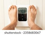 Small photo of A man's feet on a weight scale. Translation:Weight, low, high, slightly high, standard, previous value, long press