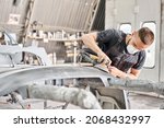 Small photo of The mechanic works with a grinding tool. Sanding of car elements. Painting car service. Repairing car section after the accident.