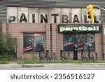 Small photo of tor, canada - august 4, 2023: paintball gladiator exterior store storefront advertisement writing caption text on brickwall with windows with pictures, bikes and road in front