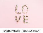 Word Love made of eucalyptus branches on pink background. Valentine's Day concept. Flat lay, top view.