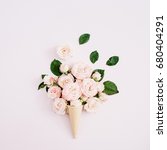 Small photo of Waffle cone with pink bombastic roses bouquet on pale pastel pink background. Flat lay, top view