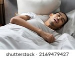 Small photo of A young bearded man sleeps with his mouth open and makes a loud snore lying down on bed, tired and deep sleep. Making noise and annoying his partner.