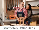 A carpenter's wife hugs her husband from behind to give him encouragement to work, feeling happiness with a smiling face at carpentry shop. Joiner, woodcraft, furniture, handmade, timber, wood