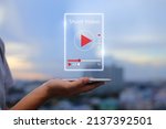 Short Video marketing concept. Man hands holding mobile phone showing virtual short video player with blurred city as background