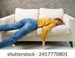 Small photo of tired young woman sleeping on the couch, feet on the floor. a very tired girl fell on the sofa from impotence