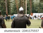 Small photo of Medieval festival of chivalry and fighting in open air, back view of fighting in chain mail and with a spear.