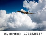 A white 4-engine passenger plane maneuvers between large clouds. Travel and transportation concept.