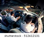 The view from the passenger aircraft cockpit. Pilots at work. The airplane climbs over the cityscape and skyscrapers at sunset.