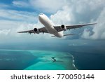 A passenger plane in the cloudy sky. Aircraft flies over the sea and the tropical island.