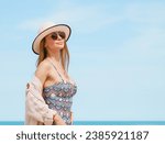 Small photo of This captivating stock photo features a young woman exuding confidence and elegance as she strikes a graceful pose on a sun-kissed sandy beach. She wears a stylish swimsuit that complements natura