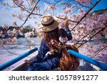 Hipster woman is sightseeing cherry blossom on the row boat while traveling during spring season at Chidorigafuchi boat parking inside the Kitanomaru Park in Tokyo, Japan.