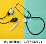 Medical equipment on a colored paper background. Stethoscope, syringe, thermometer, tonometer. Top view, flat lay.
