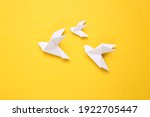 Origami paper doves on a yellow background. Peace symbol
