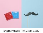 Packets of condoms with a mustache on a stick. Blue pink pastel background