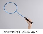 Hand holding batbinton racket on gray background