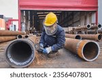 Small photo of Houston, Texas United States of America - August 30, 2023: Man in safety gear like a helmet, visor, and vest. welding on a rusted metal pipe. a man using a handheld electrical saw on a metal pipe.