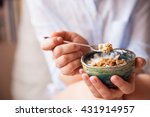 Young woman with muesli bowl. Girl eating breakfast cereals with nuts, pumpkin seeds, oats and yogurt in bowl. Girl holding homemade granola. Healthy snack or breakfast in the morning..