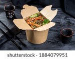 paper box with vegetarian buckwheat noodle wok. decor on a black background.