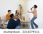 Small photo of Group of Asian friends playing karaoke and sing a song at home together