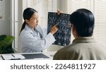 Small photo of Young Asian woman doctor showing lung x-ray test results and describe to a senior patient in hospital. For cancer awareness month