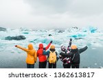 Five young girls standing on the sea shore covered in ice floes looking at the Nordic landscape in Iceland and enjoying life