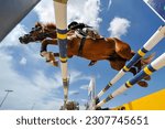 The bottom view on the rider on horse jumping over a hurdle during the equestrian event