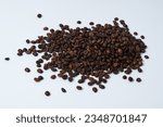 Small photo of A small pile of whole roasted coffee beans isolated on a white background. The concept of vivacity and good mood