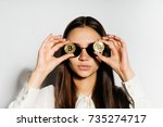 steep, serious girl with black glasses put a coin to her eyes.bitcoins, isolated