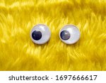 Small photo of Funny Wiggle Google Eyes on Fabric Silly Yellow Furry Background