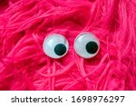 Small photo of Funny Wiggle Google Eyes on Fabric Silly Pink Fur Carpet Background