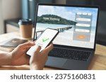 Small photo of Hand using laptop and booking hotel on website for vacation after a long work and payment completed message on mobile, Summer holiday concept.