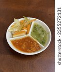 Small photo of Spicy chili sauce, pickles, green sambel served on a white bulkhead plate