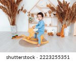 A boy riding a wooden rocking...