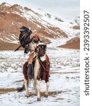 Small photo of Ulgii, Mongolia - October, 01, 2023: Portrait of a male hunter on horseback with a hunting golden eagle. Eagle hunters are individuals who train and hunt with golden eagles. Northern Mongolia.