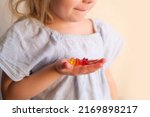 Small photo of small child, blonde girl 3 years old wants to eat gelatinous sweets, gummy bear, kid has a good appetite, happy childhood, balanced diet, sweet life, unhealthy food, halal food