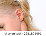 Small photo of ear small patient, child, girl 3 years old, part face in profile close-up, medical concept, pierce ears, middle ear inflammation, otitis media, diagnosis and treatment of ophthalmic, ear diseases