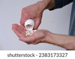 Small photo of male hand spilling, stretches on palm white pills, capsule or vitamins on blurred light background, concept panacea for all diseases, placebo pill, overdose, people drug addiction problems