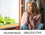 Adult woman taking tea pensive looking out the window