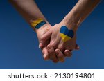 female hands painted in Ukraine flag colors yellow-blue holding. Stop the war and the power of Ukraine, patriotism and Kiev, strength and power