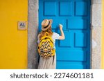 Small photo of Rear back view of young tourist woman knocking the door of the AL - Alojamento local - typical accommodation in Portugal. enjoying a vacation in Europe.
